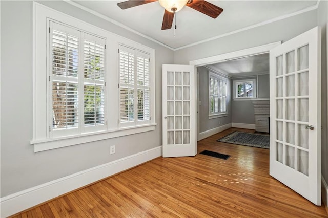 spare room with a wealth of natural light, crown molding, and hardwood / wood-style flooring