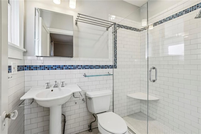 bathroom featuring toilet, a shower with door, and tile walls