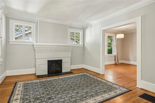 unfurnished living room featuring ornamental molding, wood-type flooring, and a brick fireplace