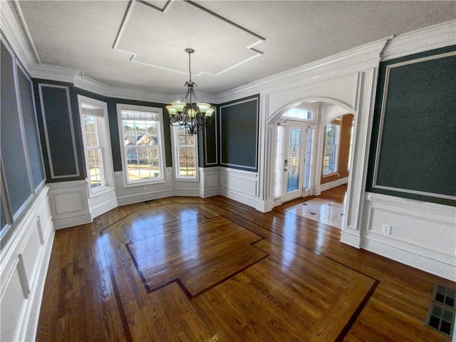 unfurnished dining area with dark hardwood / wood-style floors, crown molding, and a chandelier