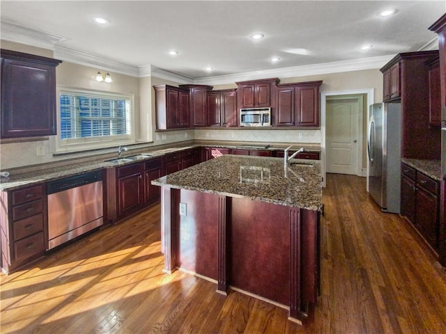 kitchen with appliances with stainless steel finishes, an island with sink, ornamental molding, and tasteful backsplash