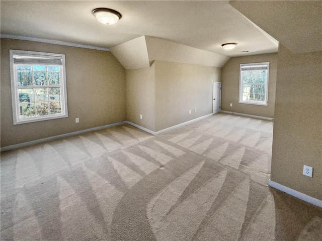 bonus room with lofted ceiling, light carpet, and a healthy amount of sunlight