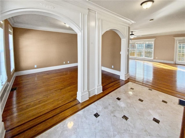 tiled empty room featuring ceiling fan and crown molding