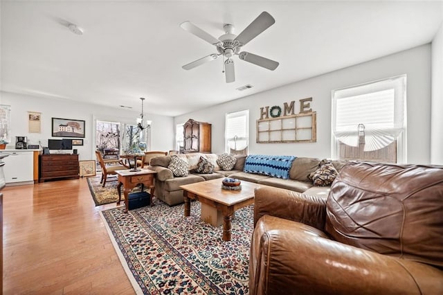 living room featuring ceiling fan with notable chandelier and light hardwood / wood-style floors