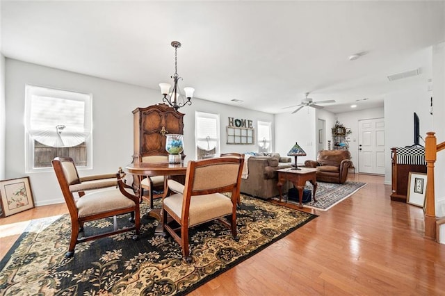 dining area with hardwood / wood-style flooring and ceiling fan with notable chandelier