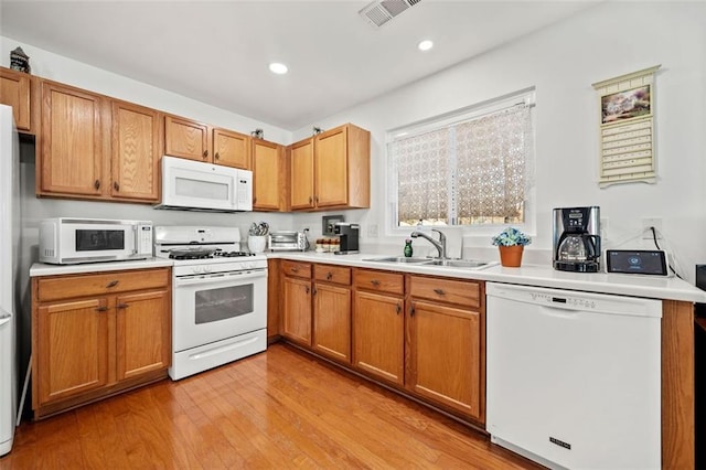 kitchen featuring white appliances, light hardwood / wood-style floors, and sink