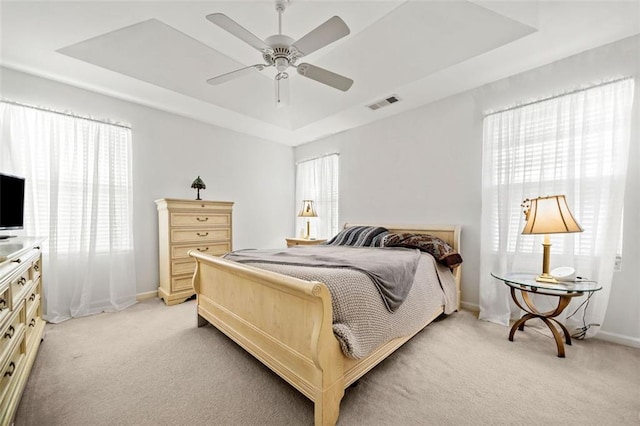 carpeted bedroom featuring ceiling fan and a tray ceiling