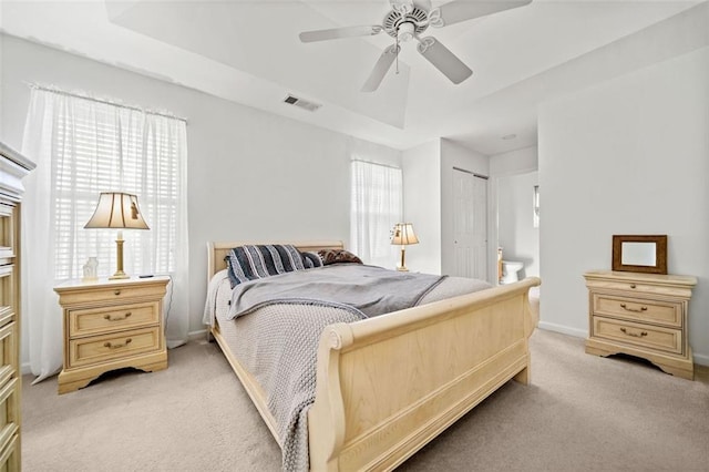 carpeted bedroom featuring ceiling fan, a raised ceiling, and a closet