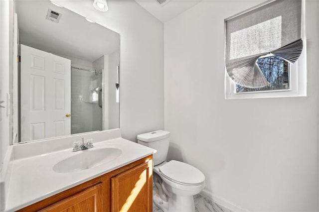 bathroom with vanity, tiled shower, and toilet