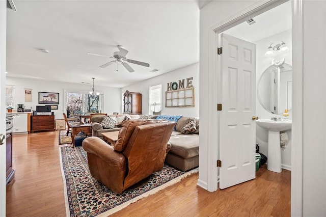 living room featuring sink, light hardwood / wood-style floors, and ceiling fan