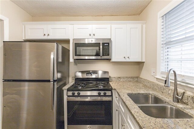 453 Utoy Cir SW, Atlanta, GA 30331 - kitchen with light stone countertops, a textured ceiling, stainless steel appliances, sink, and white cabinets