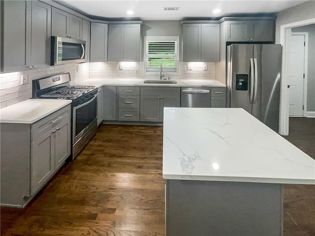 kitchen featuring light stone countertops, dark hardwood / wood-style floors, stainless steel appliances, gray cabinets, and sink