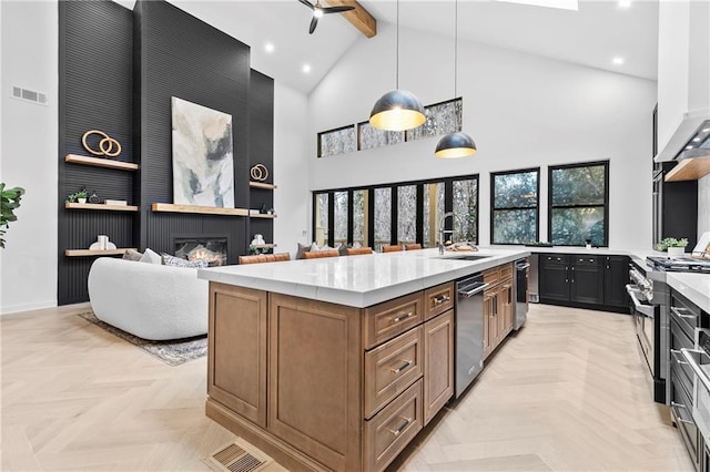 kitchen featuring stainless steel appliances, sink, an island with sink, pendant lighting, and light parquet flooring