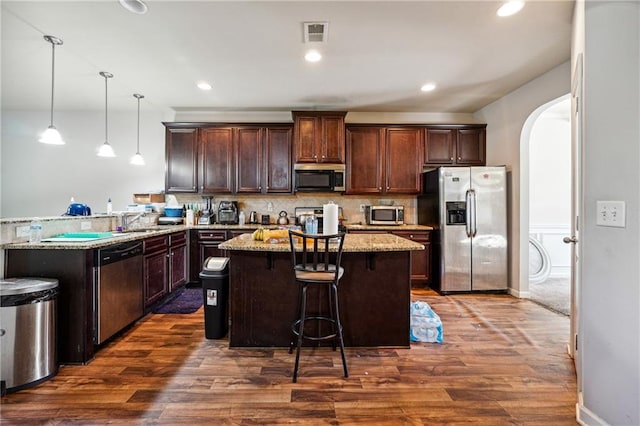 kitchen featuring pendant lighting, a kitchen breakfast bar, dark wood-type flooring, and stainless steel appliances