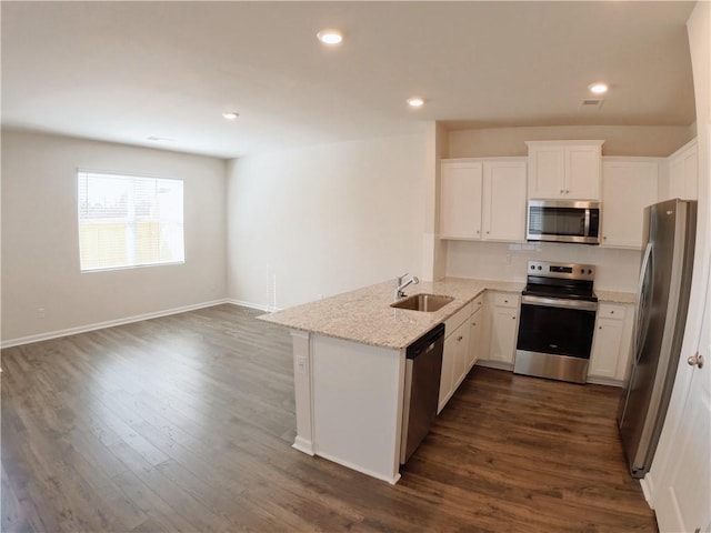 kitchen with sink, white cabinetry, stainless steel appliances, light stone counters, and kitchen peninsula