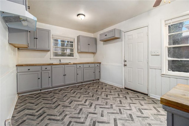 kitchen featuring sink, gray cabinets, wooden counters, and ceiling fan