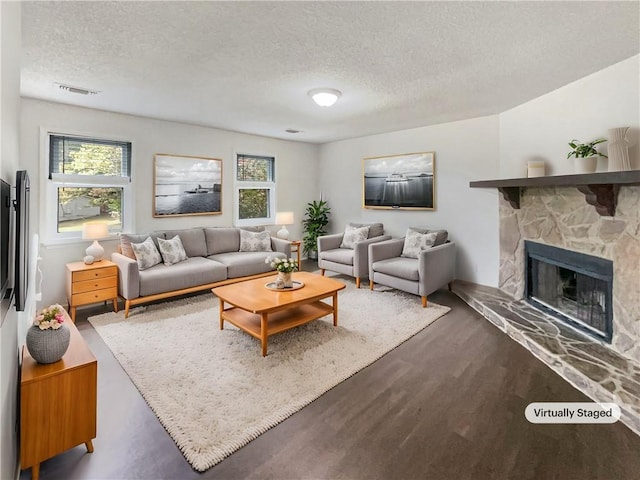 living room featuring dark wood-type flooring, a textured ceiling, and a fireplace