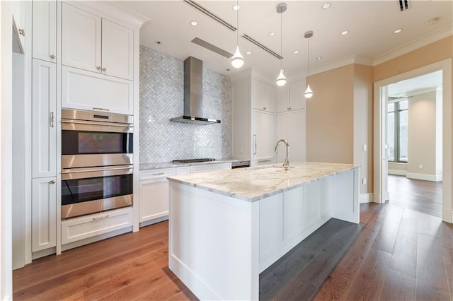 3376 Peachtree Rd NE Unit 35A, Atlanta, GA 30326 - kitchen with wall chimney range hood, stainless steel double oven, a sink, white cabinetry, and ornamental molding