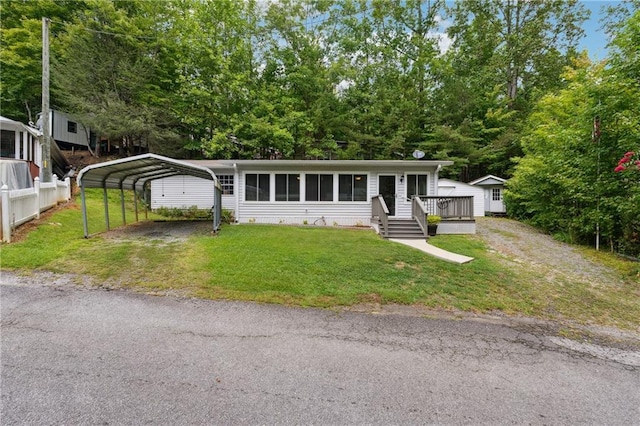 view of front of home featuring a storage shed, an outbuilding, a carport, driveway, and a front yard