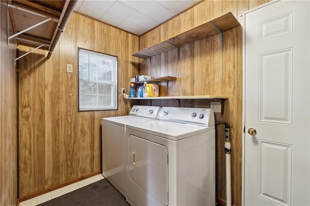 clothes washing area featuring washer and dryer, laundry area, and wooden walls