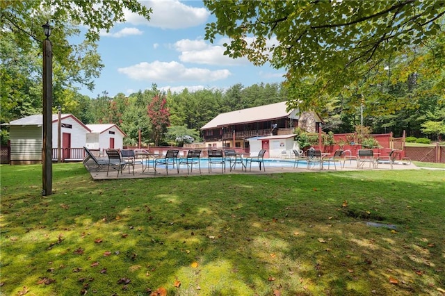 view of pool with a fenced in pool, fence, a yard, a shed, and an outdoor structure