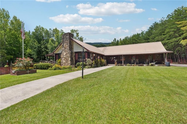 view of front of property featuring metal roof, a chimney, a front yard, and covered porch