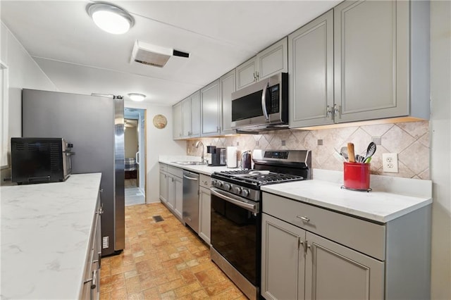 kitchen with tasteful backsplash, appliances with stainless steel finishes, and gray cabinets