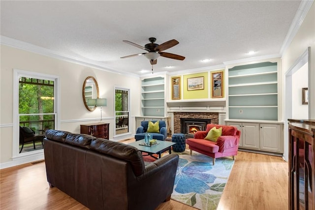 130 Wayne Wheeler Way, Woodstock, GA 30188 - living room with light wood-style flooring, ceiling fan, a stone fireplace, crown molding, and a textured ceiling