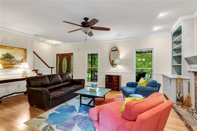 130 Wayne Wheeler Way, Woodstock, GA 30188 - living room featuring wood finished floors, a ceiling fan, a fireplace with raised hearth, ornamental molding, and stairway