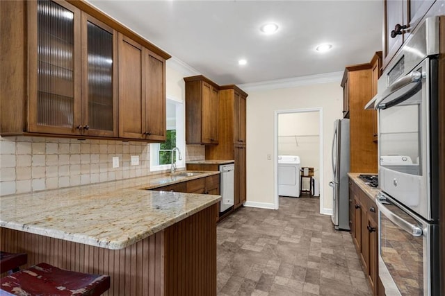 130 Wayne Wheeler Way, Woodstock, GA 30188 - kitchen with washer / dryer, ornamental molding, stainless steel appliances, backsplash, and a peninsula