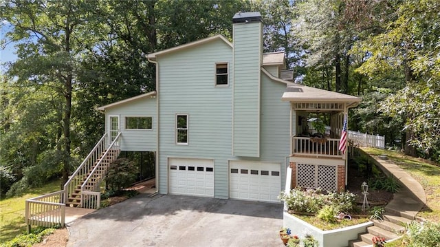 130 Wayne Wheeler Way, Woodstock, GA 30188 - view of property exterior with stairs, a garage, concrete driveway, a chimney, and view of scattered trees