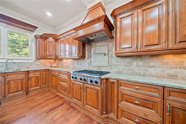 kitchen featuring custom range hood, a sink, brown cabinets, and stainless steel gas stovetop