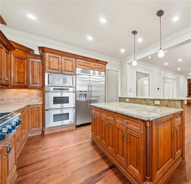 kitchen featuring light wood-type flooring, light stone counters, brown cabinets, and built in appliances