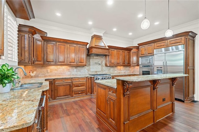 kitchen with custom range hood, brown cabinetry, a sink, and built in appliances