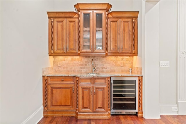 bar featuring dark wood-style flooring, decorative backsplash, a sink, wet bar, and beverage cooler