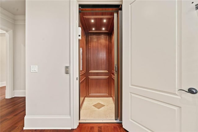 details with baseboards, wood finished floors, and elevator