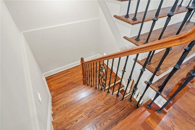 stairway with wood finished floors and baseboards