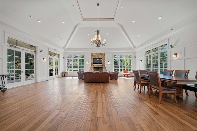 sunroom / solarium featuring french doors, a notable chandelier, plenty of natural light, and a stone fireplace