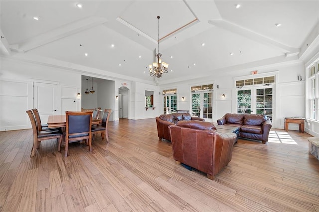 living room with light wood-style flooring, a high ceiling, and a chandelier