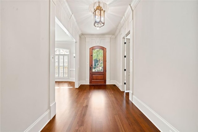 entrance foyer featuring a chandelier, dark wood finished floors, baseboards, and ornamental molding