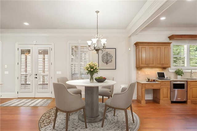 dining area with french doors, an inviting chandelier, light wood-style flooring, and crown molding