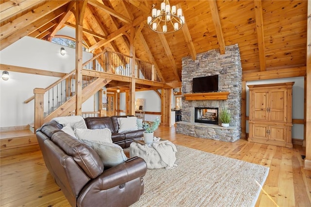living room featuring hardwood / wood-style floors, a chandelier, beamed ceiling, high vaulted ceiling, and a stone fireplace