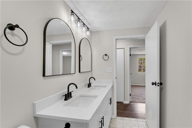 3414 Dearwood Dr SW, Lilburn, GA 30047 - bathroom featuring a textured ceiling, double vanity, baseboards, and tile patterned flooring