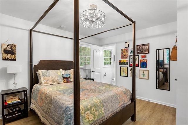 bedroom with baseboards, wood finished floors, and a chandelier