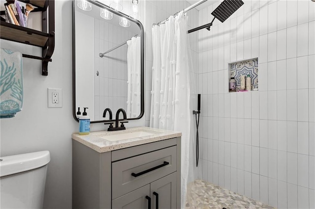 bathroom featuring vanity, toilet, and tiled shower