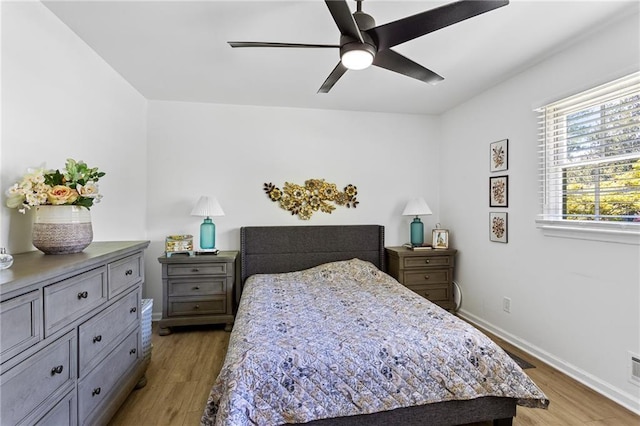 bedroom with a ceiling fan, baseboards, and light wood-style flooring