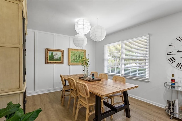 dining area featuring light wood-style flooring and a decorative wall