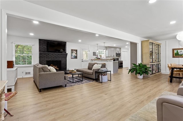 living room with recessed lighting, visible vents, light wood-type flooring, and a fireplace