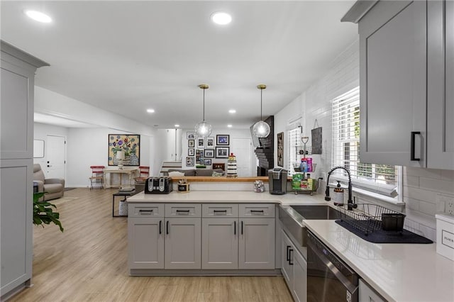 kitchen featuring stainless steel dishwasher, gray cabinetry, a sink, a peninsula, and open floor plan