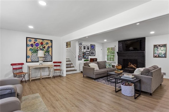 living room featuring wood finished floors, a fireplace, baseboards, stairway, and recessed lighting